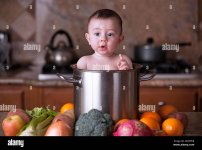 cute-baby-boy-sitting-in-stainless-steel-pot-colander-in-the-kitchen-2DX3PDR.jpg